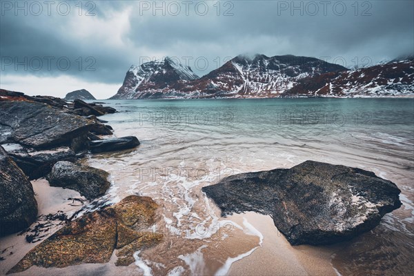 Rocky coast of fjord of Norwegian sea in winter with snow. Haukland beach