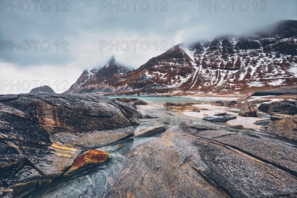 Rocky coast of fjord of Norwegian sea in winter with snow. Haukland beach