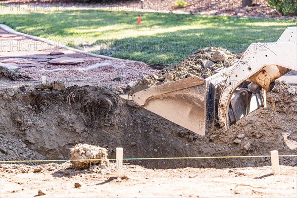 Small bulldozer digging in yard for pool installation