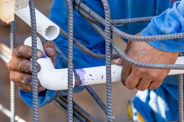 Plumber installing PVC pipe at construction site