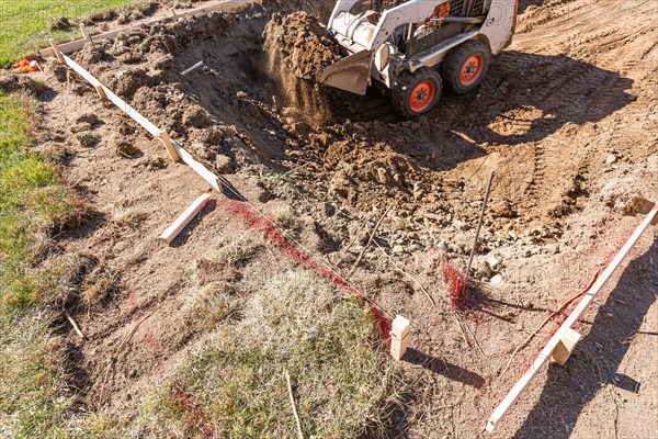 Small bulldozer digging in yard for pool installation