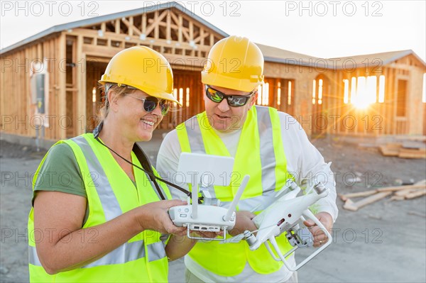Workers with drone quadcopter inspecting photographs on controller at contruction site