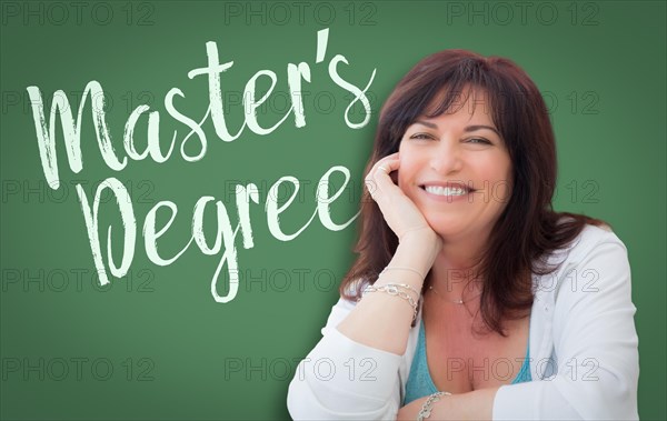 Master's degree written on green chalkboard behind smiling middle aged woman