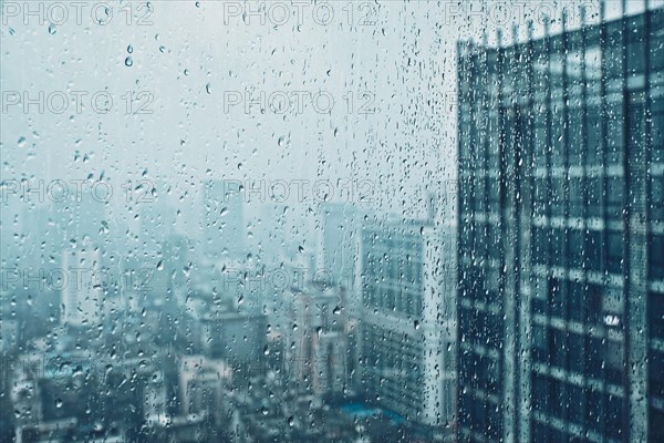 Rain water drops droplets on window glass texture with skyscrapers in background