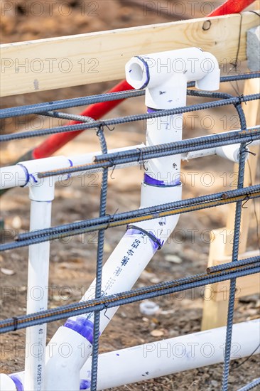 Newly installed PVC plumbing pipes and steel rebar configuration at construction site