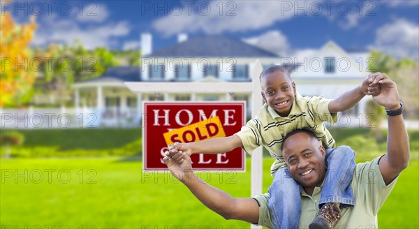 Happy african american father and son in front of new home and sold real estate sign