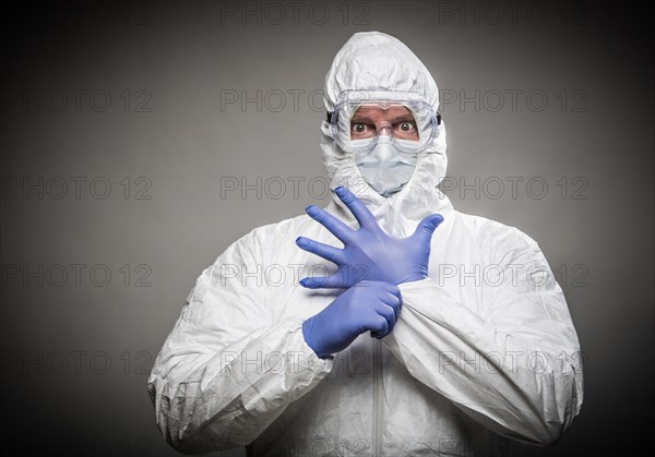 Man with intense expression wearing HAZMAT protective clothing against A gray background