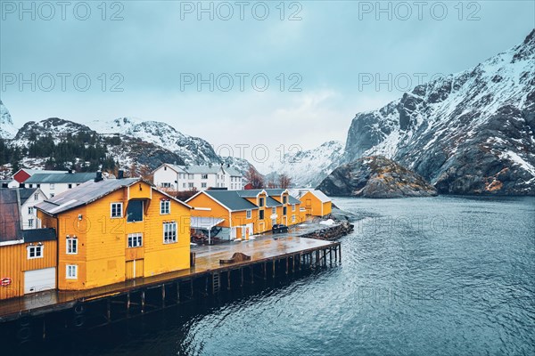 Panorama of Nusfjord authentic fishing village with yellow rorbu houses in Norwegian fjord in winter. Lofoten islands