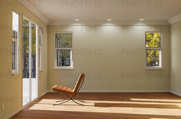 Empty chair sitting on the floor facing glass door in empty room of house with blank wall