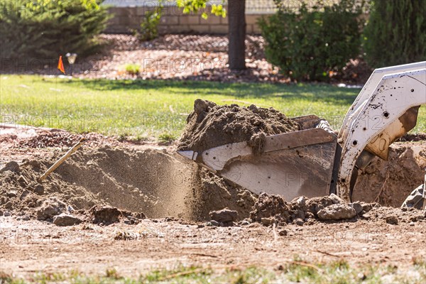 Small bulldozer digging in yard for pool installation