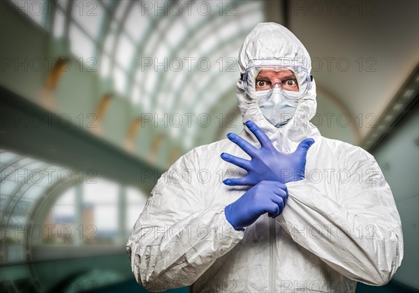 Man with intense expression wearing HAZMAT protective clothing inside building