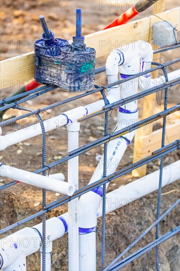 Newly installed PVC plumbing pipes and steel rebar configuration at construction site