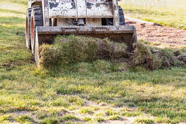 Small bulldozer removing grass from yard preparing for pool installation