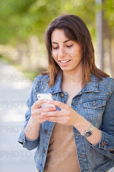 Beautiful young ethnic woman using her smartphone outside