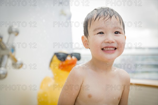 mixed-race boy having fun at the water park with large rubber duck in the background