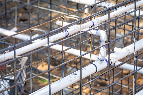 Newly installed PVC plumbing pipes and steel rebar configuration at construction site