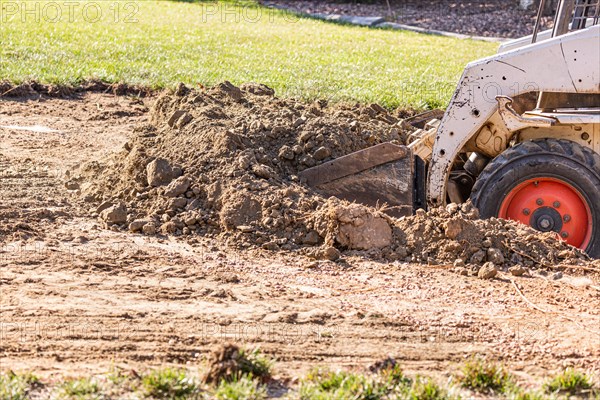 Small bulldozer digging in yard for pool installation