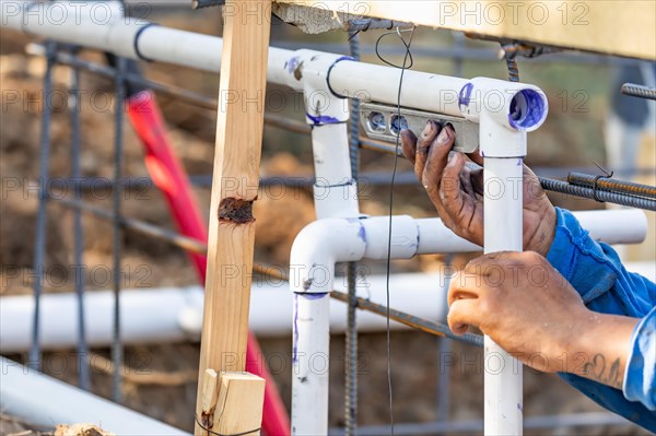 Plumber using level while installing PVC pipe at construction site