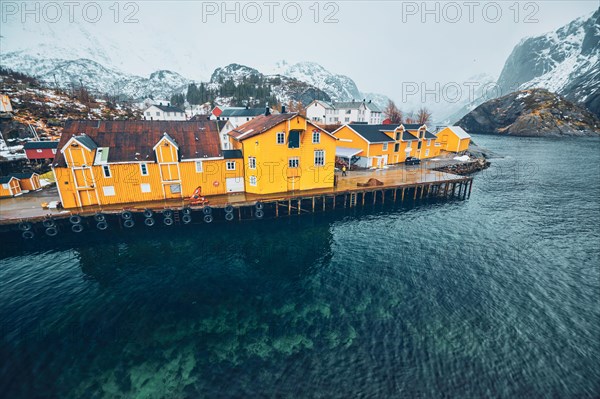 Panorama of Nusfjord authentic fishing village with yellow rorbu houses in Norwegian fjord in winter. Lofoten islands