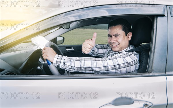 Portrait of a man showing thumbs up while driving