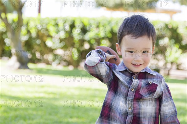 Adorable mixed-race boy playing football outside at the park