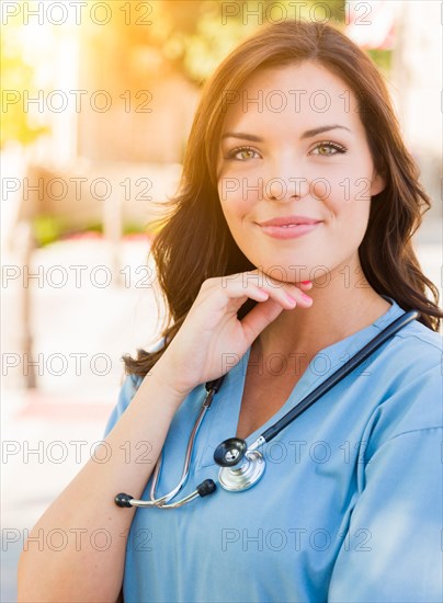 Portrait of young adult female doctor or nurse wearing scrubs and stethoscope outside