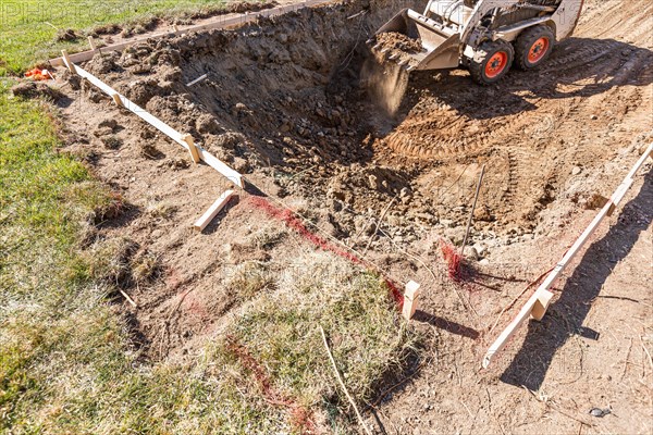 Small bulldozer digging in yard for pool installation