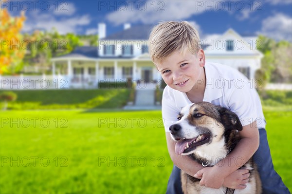 Happy young boy and his dog in front yard of their house