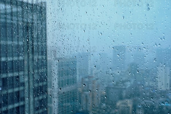 Rain water drops droplets on window glass texture with skyscrapers in background