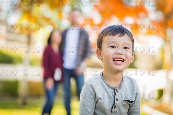 Outdoor portrait of happy mixed-race chinese and caucasian parents and child