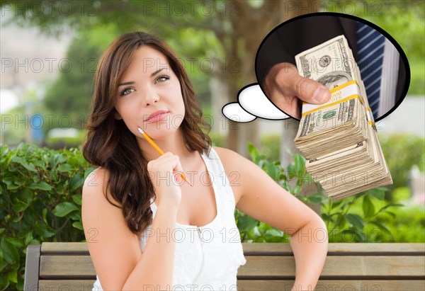 Thoughtful young woman with hand holding stack of money inside thought bubble