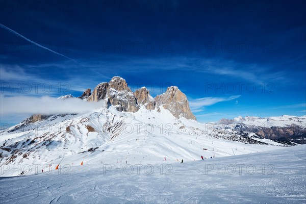 View of a ski resort piste with people skiing in Dolomites in Italy