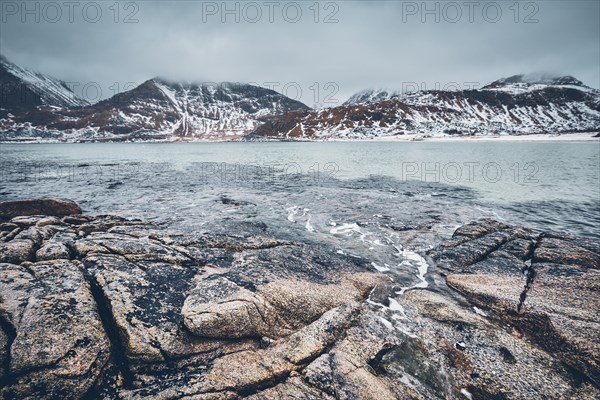 Rocky coast of fjord of Norwegian sea in winter with snow. Haukland beach