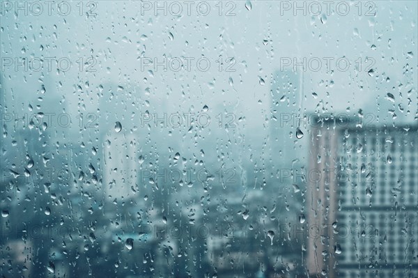 Rain water drops droplets on window glass texture with skyscrapers in background