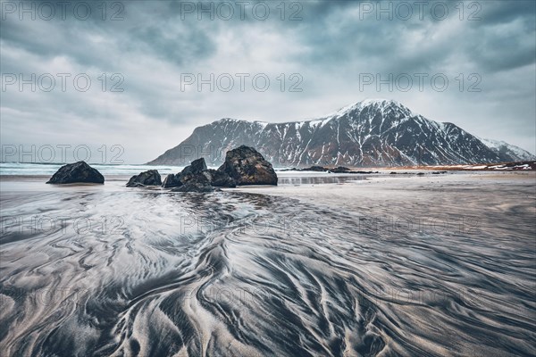 Rocks on beach of fjord of Norwegian sea in winter with snow. Skagsanden beach