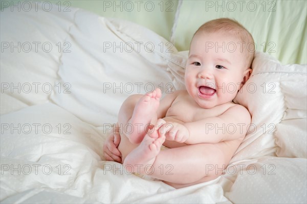 Young mixed-race chinese and caucasian baby boy having fun on his blanket