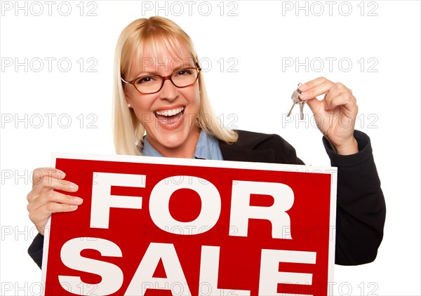 Attractive blonde holding keys & for sale sign isolated on a white background