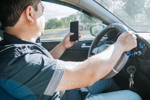 Person holding the cell phone and with the other hand the steering wheel