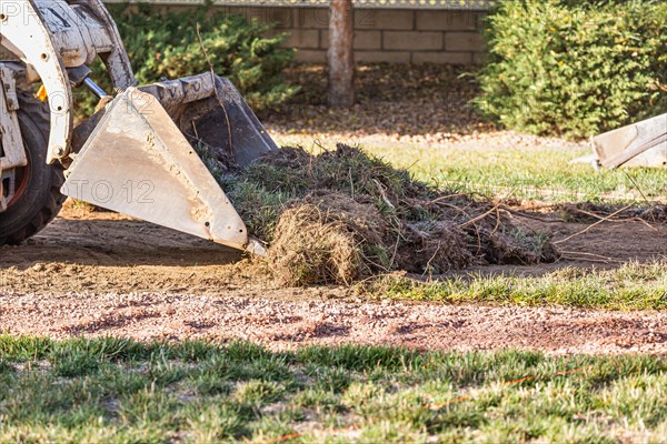 Small bulldozer removing grass from yard preparing for pool installation