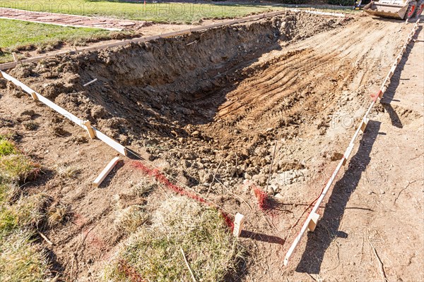 Freshly dug hole in yard preparing for swimming pool installation