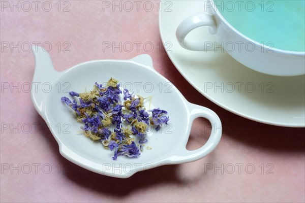 Getrocknete Malvenblueten in Schaelchen und Tasse Malvenbluetentee