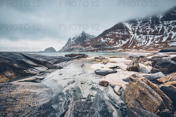 Rocky coast of fjord of Norwegian sea in winter with snow. Haukland beach