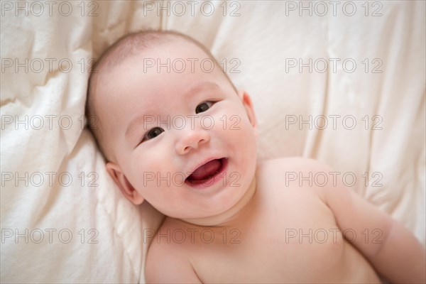 Young mixed-race chinese and caucasian baby boy having fun on his blanket