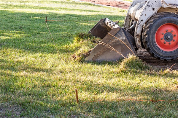 Small bulldozer removing grass from yard preparing for pool installation