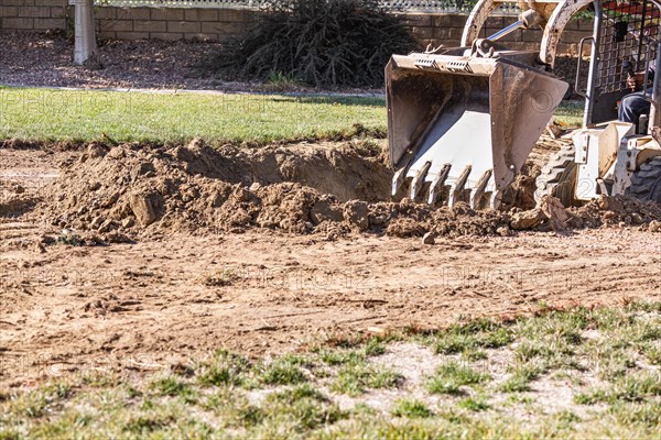 Small bulldozer digging in yard for pool installation