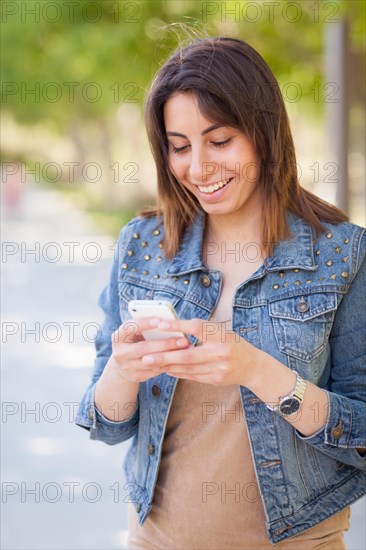 Beautiful young ethnic woman using her smartphone outside