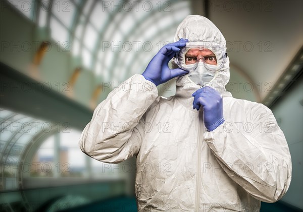 Man with intense expression wearing HAZMAT protective clothing inside building