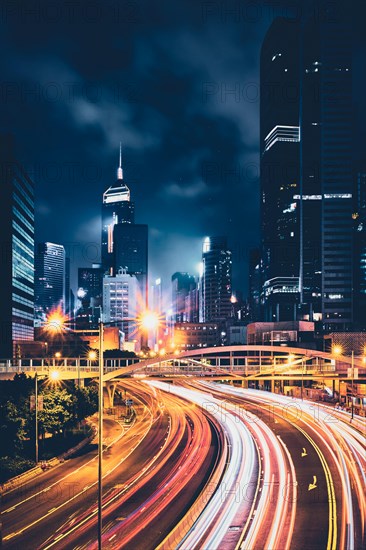 Street traffic in Hong Kong at night. Office skyscraper buildings and busy traffic on highway road with blurred cars light trails. Hong Kong