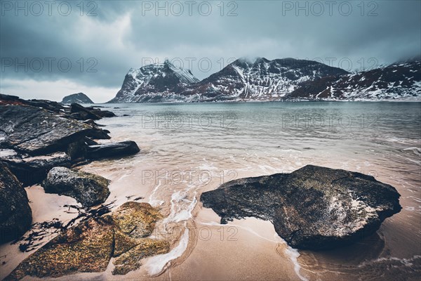 Rocky coast of fjord of Norwegian sea in winter with snow. Haukland beach