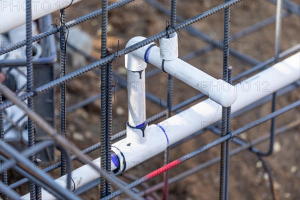 Newly installed PVC plumbing pipes and steel rebar configuration at construction site